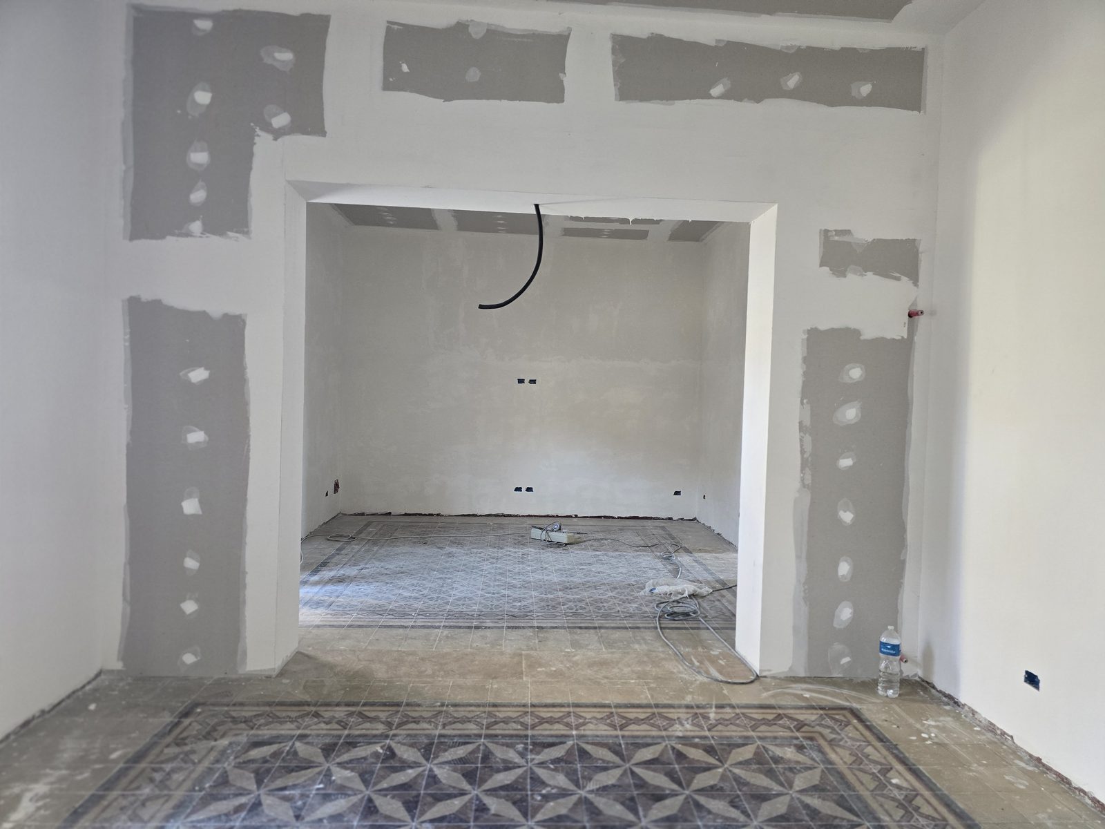 Interno in ristrutturazione: pareti in cartongesso grezzo sopra pavimento in cementine decorate originali